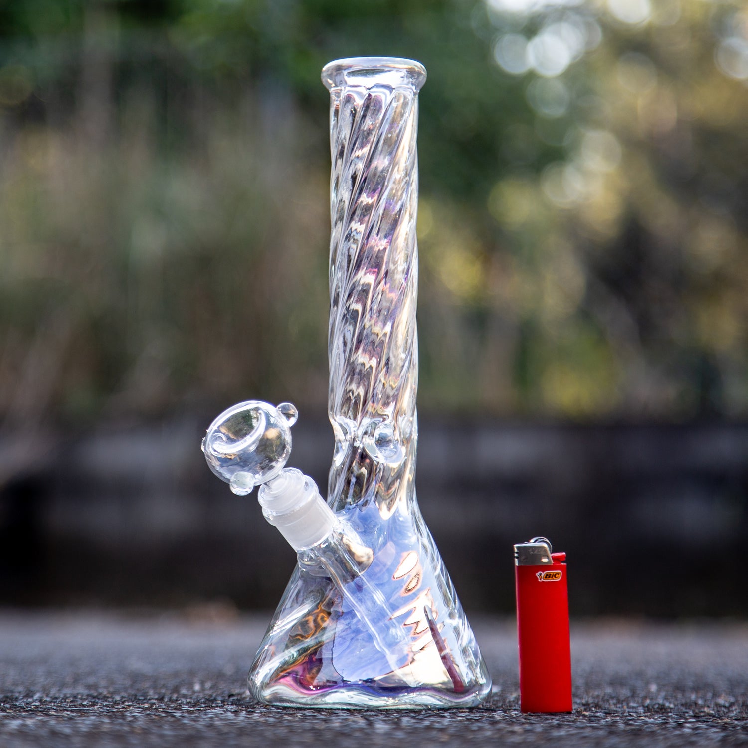 Chromatic twist glass beaker bong photographed outside.