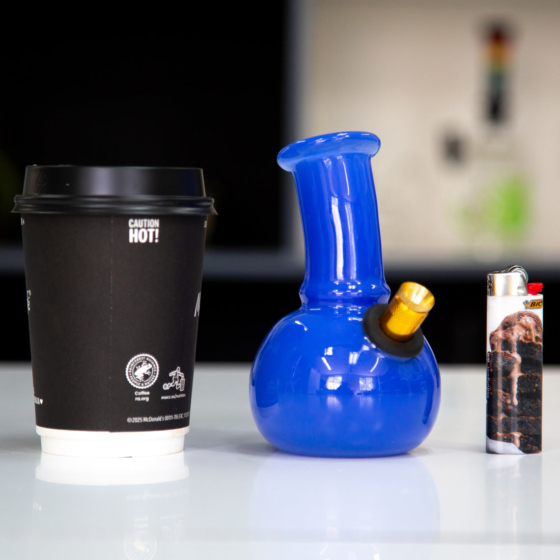Small blue Australian glass bong on table with lighter and coffee cup